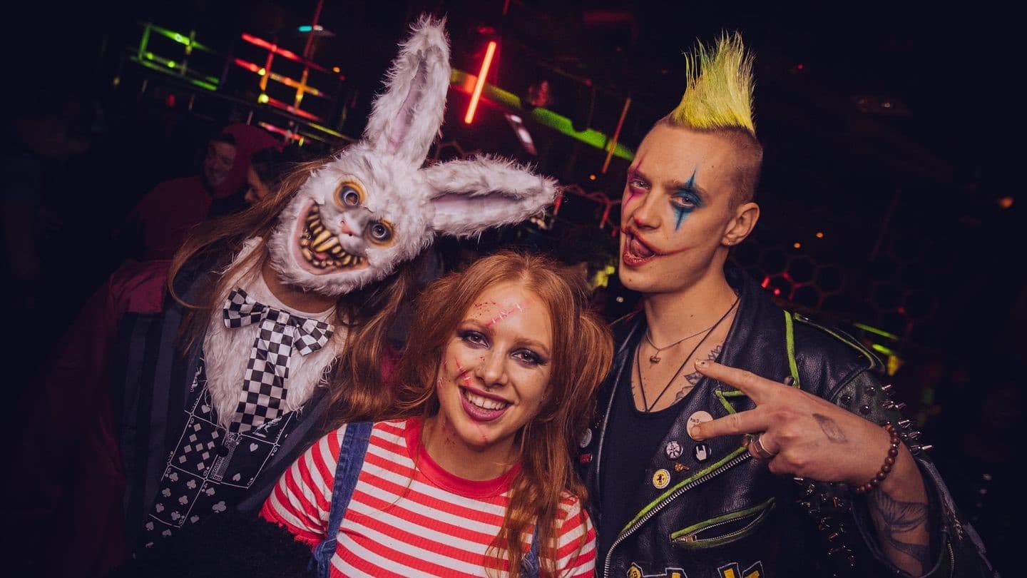 Three circus performers looking at the camera, one dressed as an evil rabbit, the other two as clowns