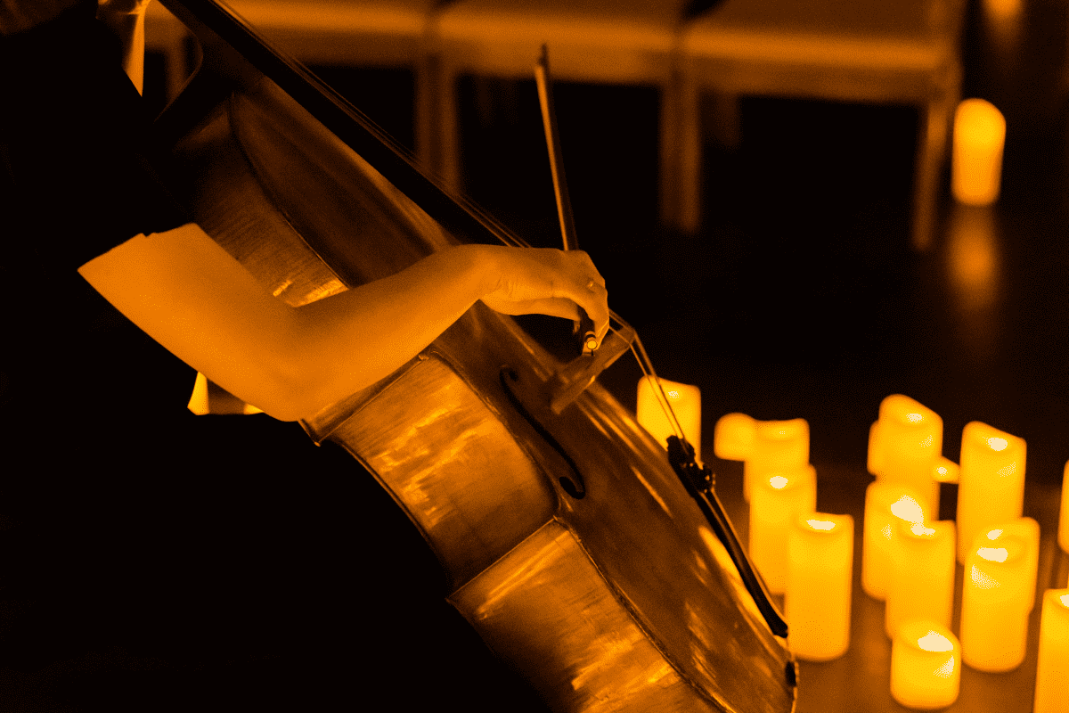 A musician playing a cello surrounded by candles