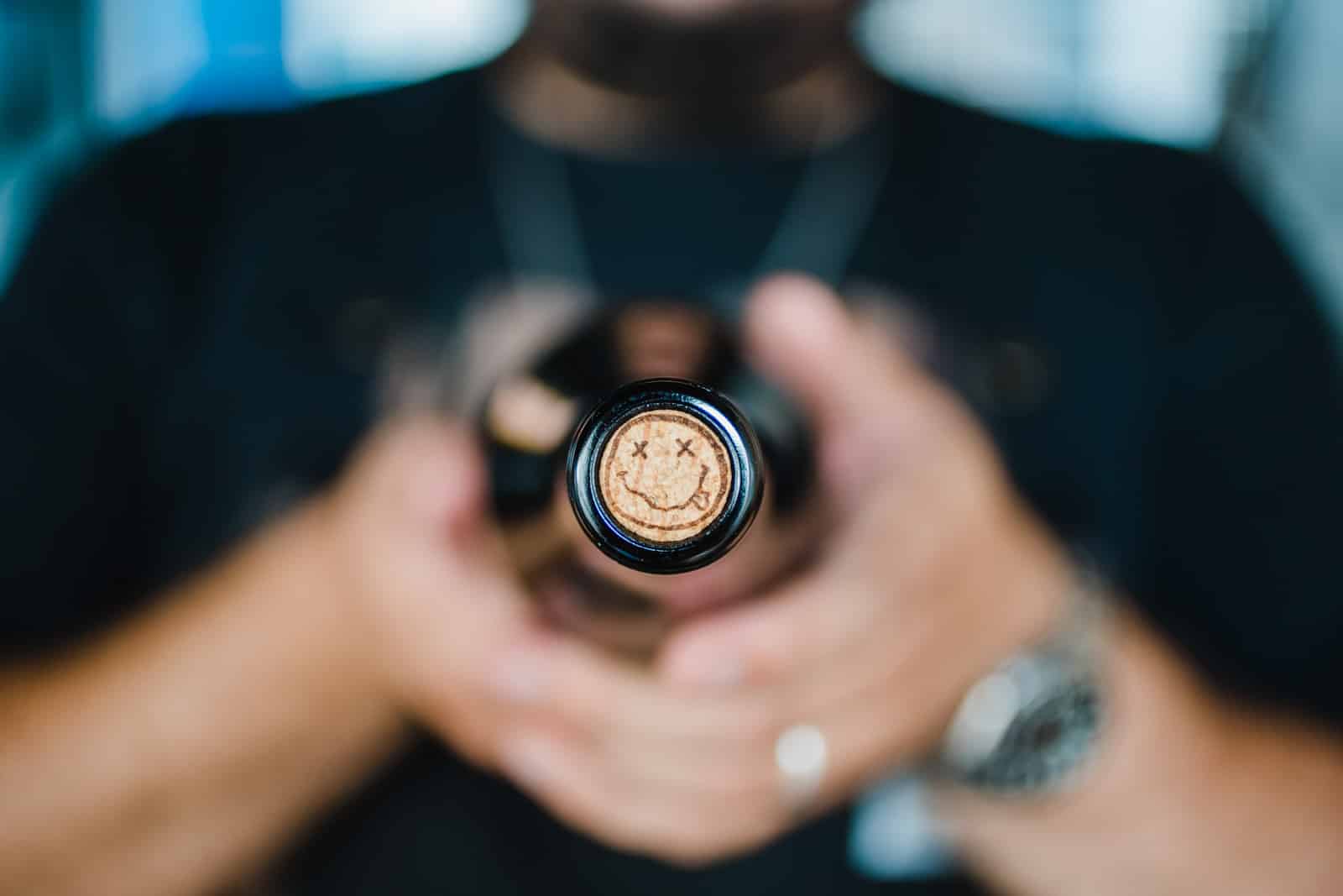 A wine bottle pointed at the camera showing the cork, with a smiley face on it