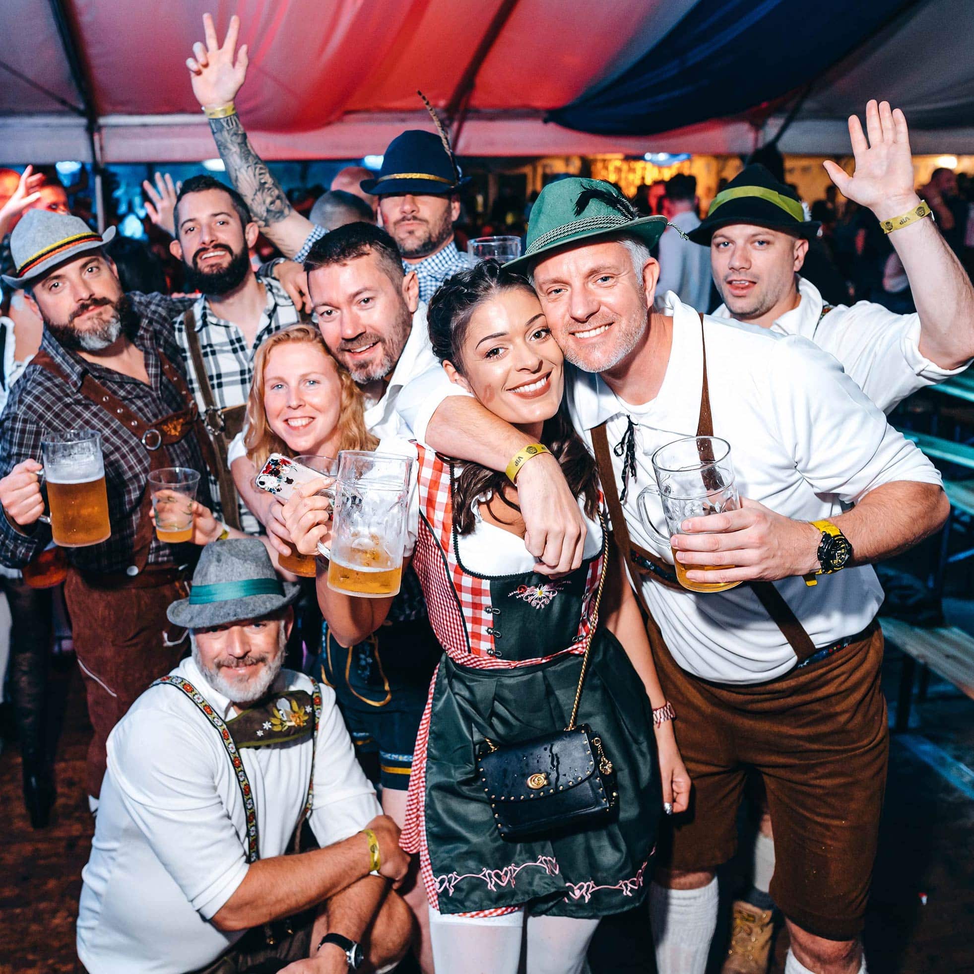 A group of people in lederhosen holding beers and celebrating Oktoberfest