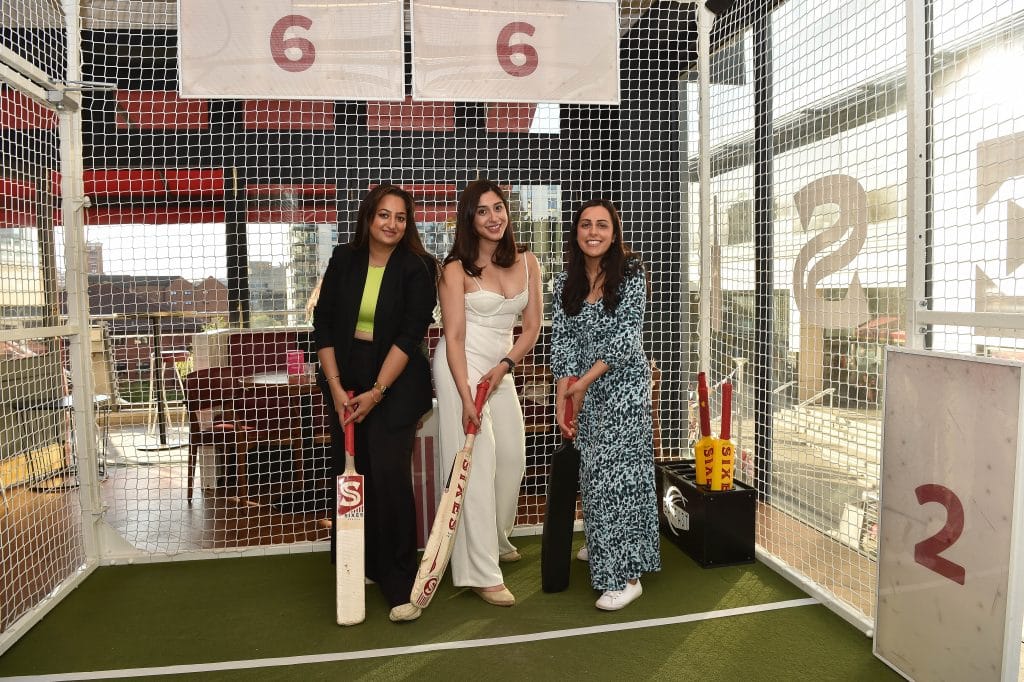 Three women holding cricket bats at Sixes