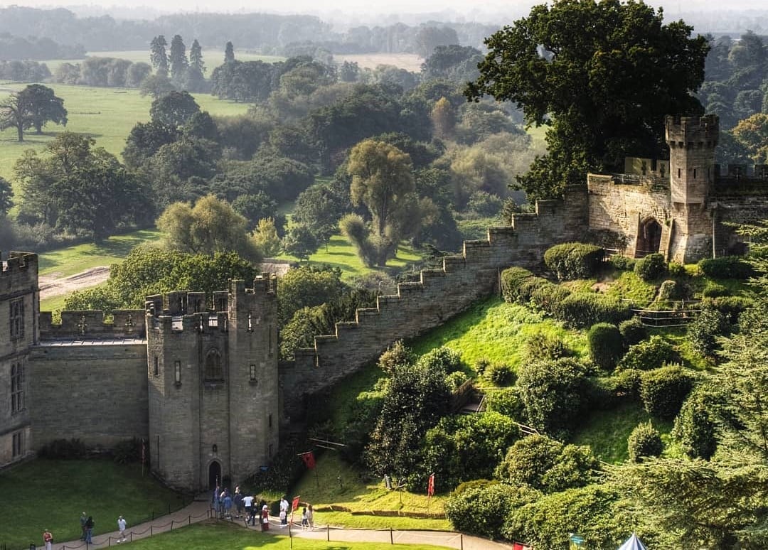 A wide shot of Warwick Castle surrounded by trees