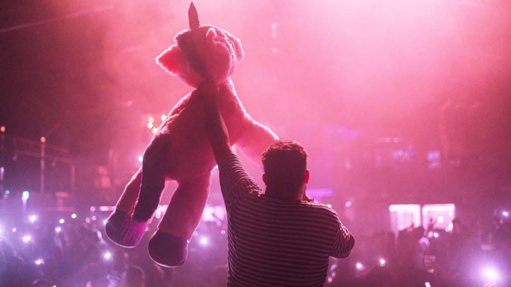A stuffed unicorn prize being held up to a crowd at Bongo's Bingo Rave