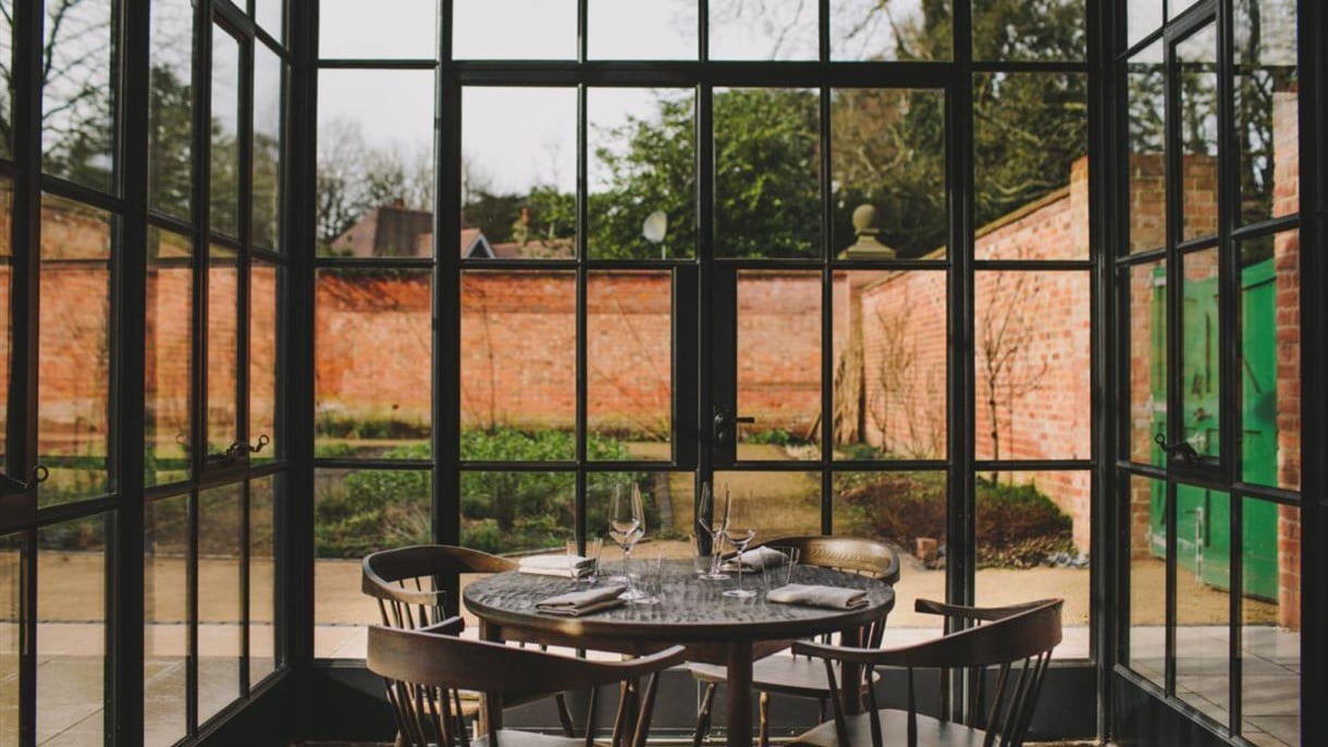 A table surrounded four chairs by a giant window overlooking a garden, Grace and Savour, one of the most exciting restaurants in Birmingham