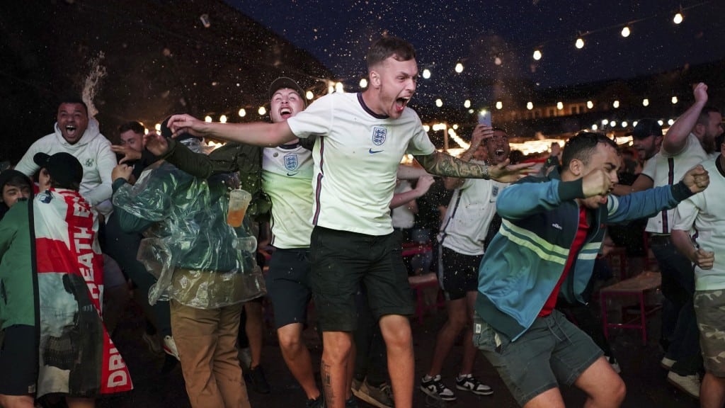 A group of people celebrating the 2022 World Cup in England kits