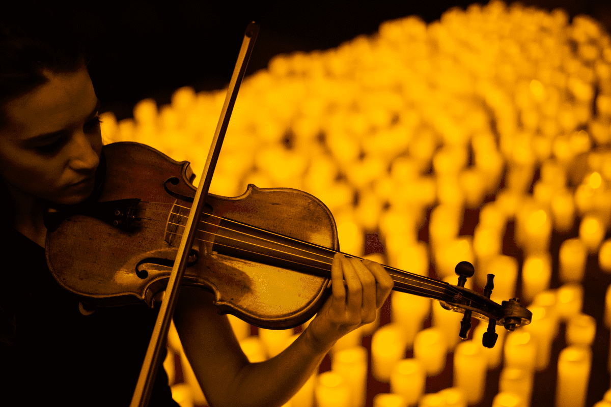 Violinist performs while surrounded by candles