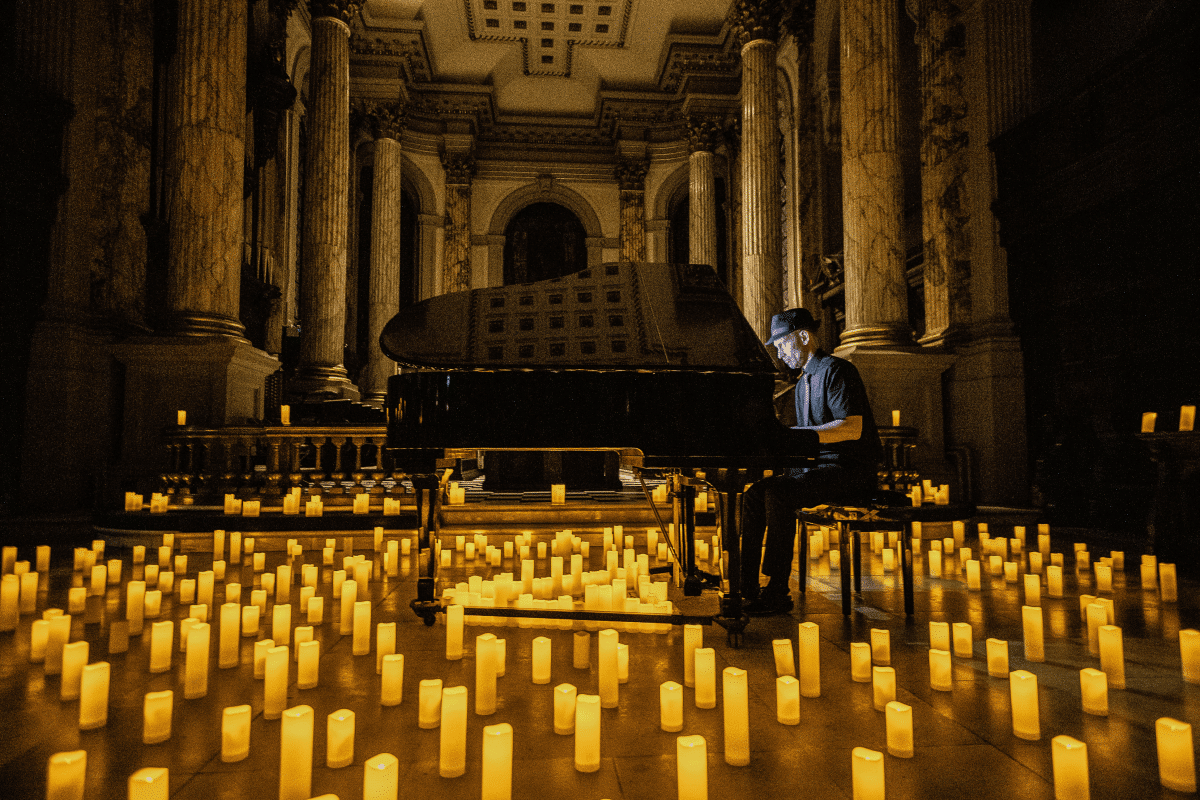 A pianist performing at a grand piano surrounded by candles.