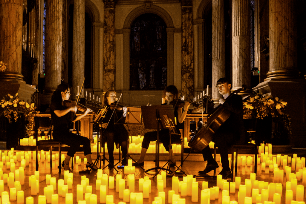 A seated string quartet performing surrounded by hundreds of candles at St. Philip's Cathedral in Birmingham