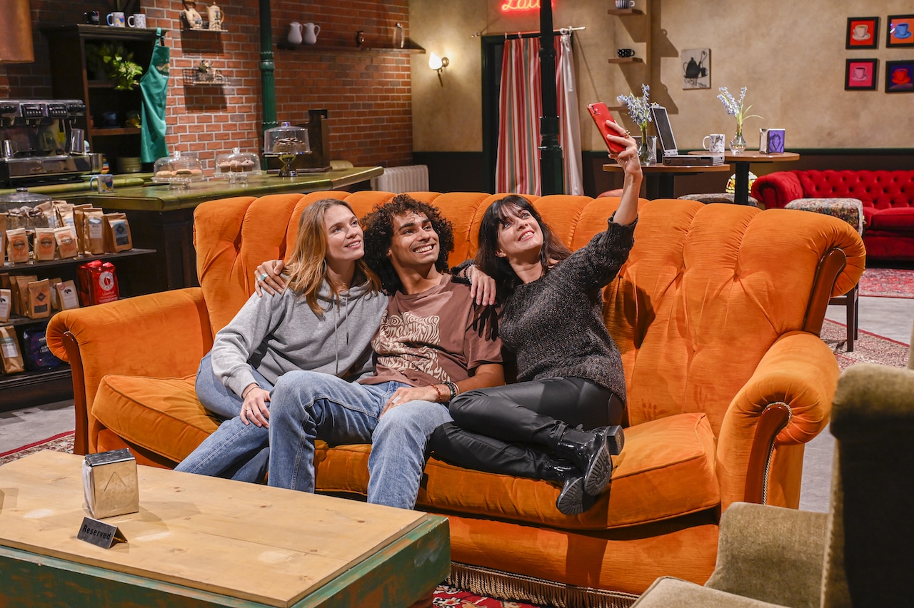 three friends taking a selfie on the iconic Central Perk orange sofa at the Friends Experience in Paris