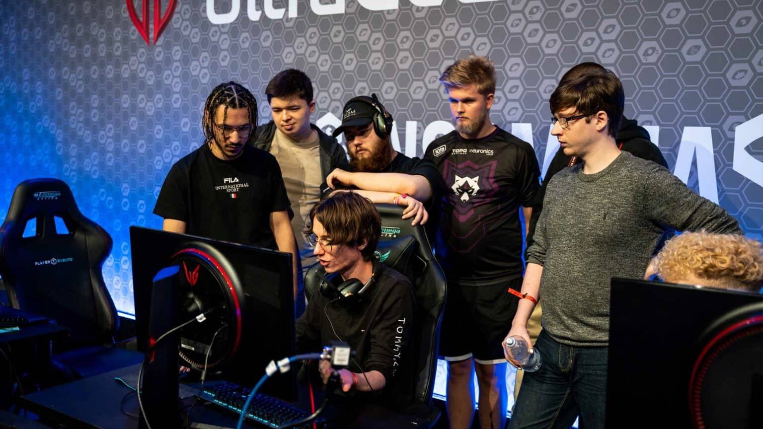 A group of men watching someone play video games on a computer at Insomnia the gaming festival