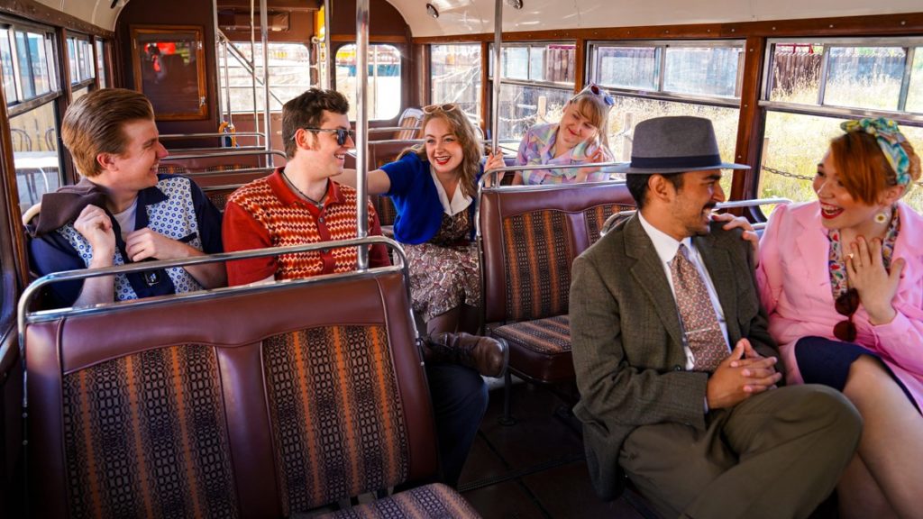 People dressed in 50s garb, sitting on an old school bus, for the 1950s-themed night at the Black Country Living Museum