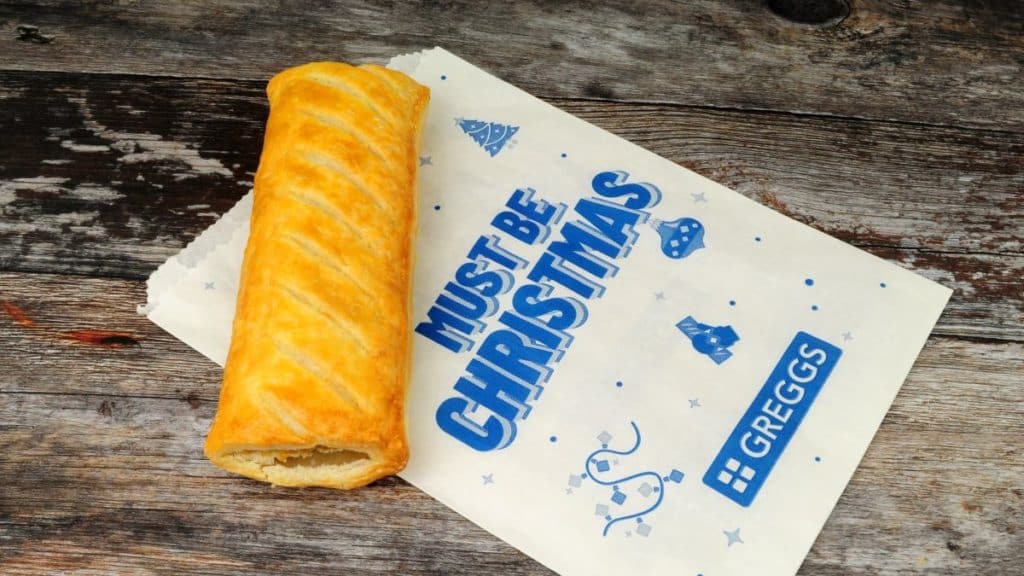 A Greggs sausage roll on a bag that reads: Must be Christmas